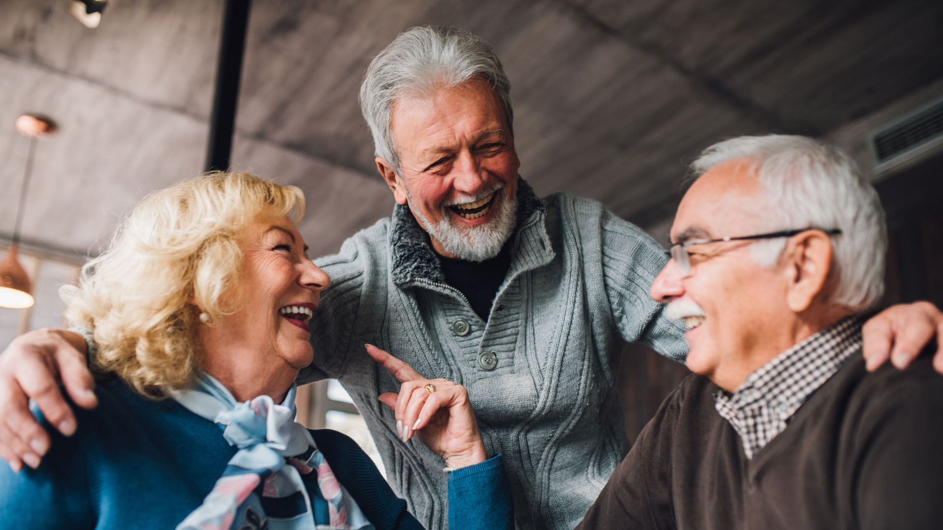 Three adults laughing together with big smiles